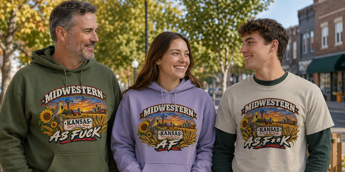 Three people on a small-town street in all three Kansas editions: green As Fuck hoodie, lilac AF hoodie, natural As F**K tee