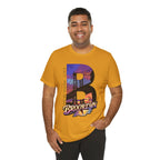 Mustard tee worn by a smiling male model, front view, with the "B" Brooklyn Bridge sunset skyline graphic.