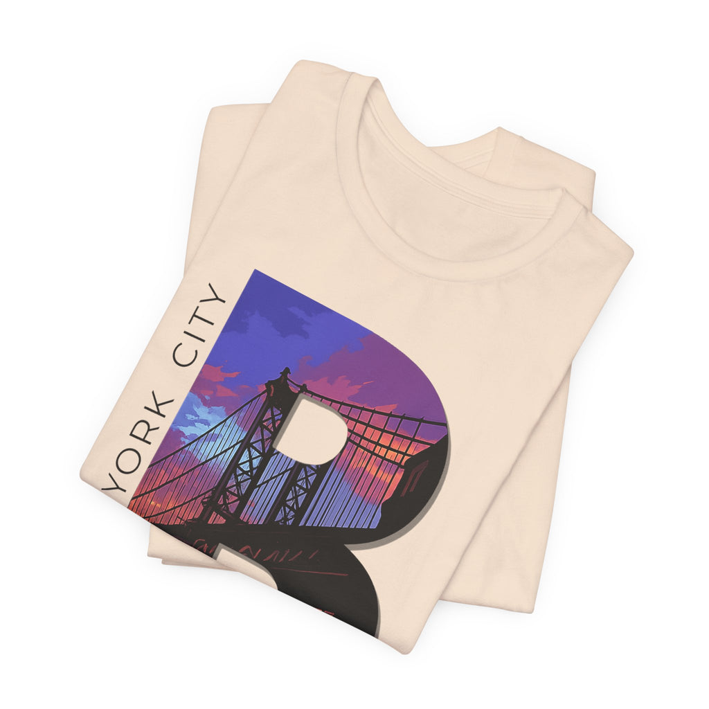 Folded stack of Vintage White tees, close-up of the "B" Brooklyn Bridge sunset skyline chest print design.