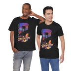 Black t-shirts worn by two male models, front view, each with a purple-orange Brooklyn Bridge sunset B graphic.