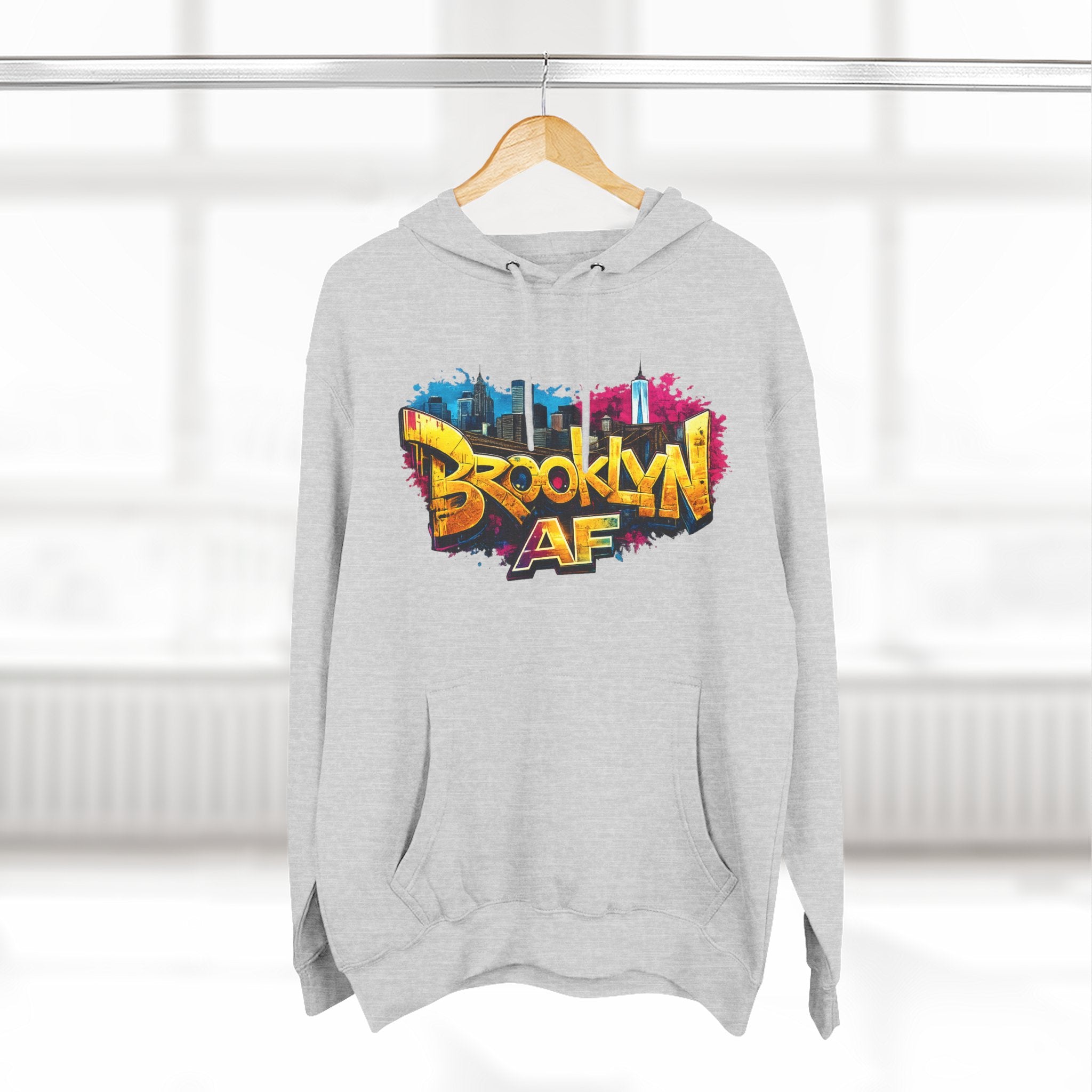 Heather Grey hoodie hanging on a wooden hanger, showing the colorful graffiti-style Brooklyn AF skyline print.