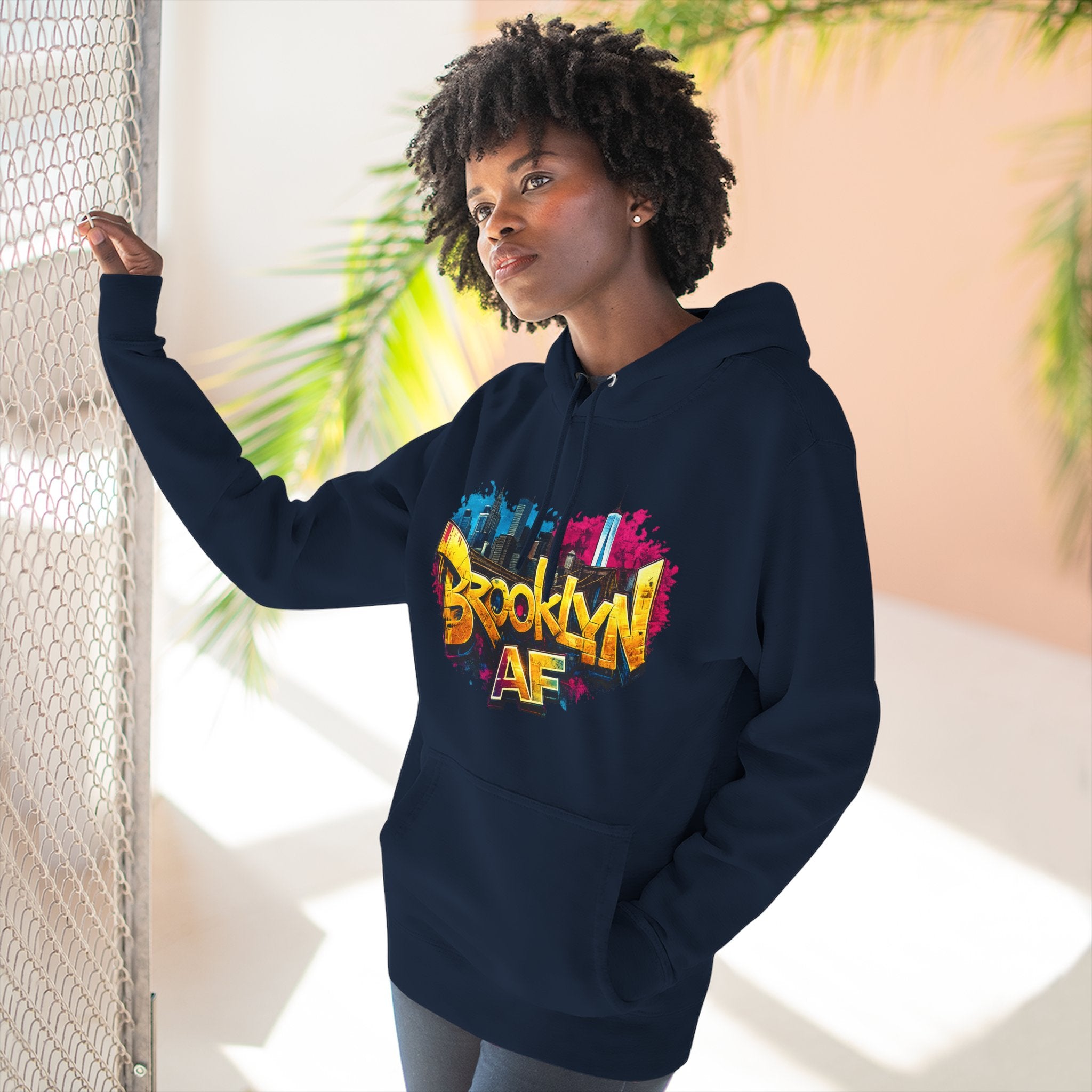 Navy hoodie worn by a female model, front view, showing the colorful graffiti-style Brooklyn AF skyline print.