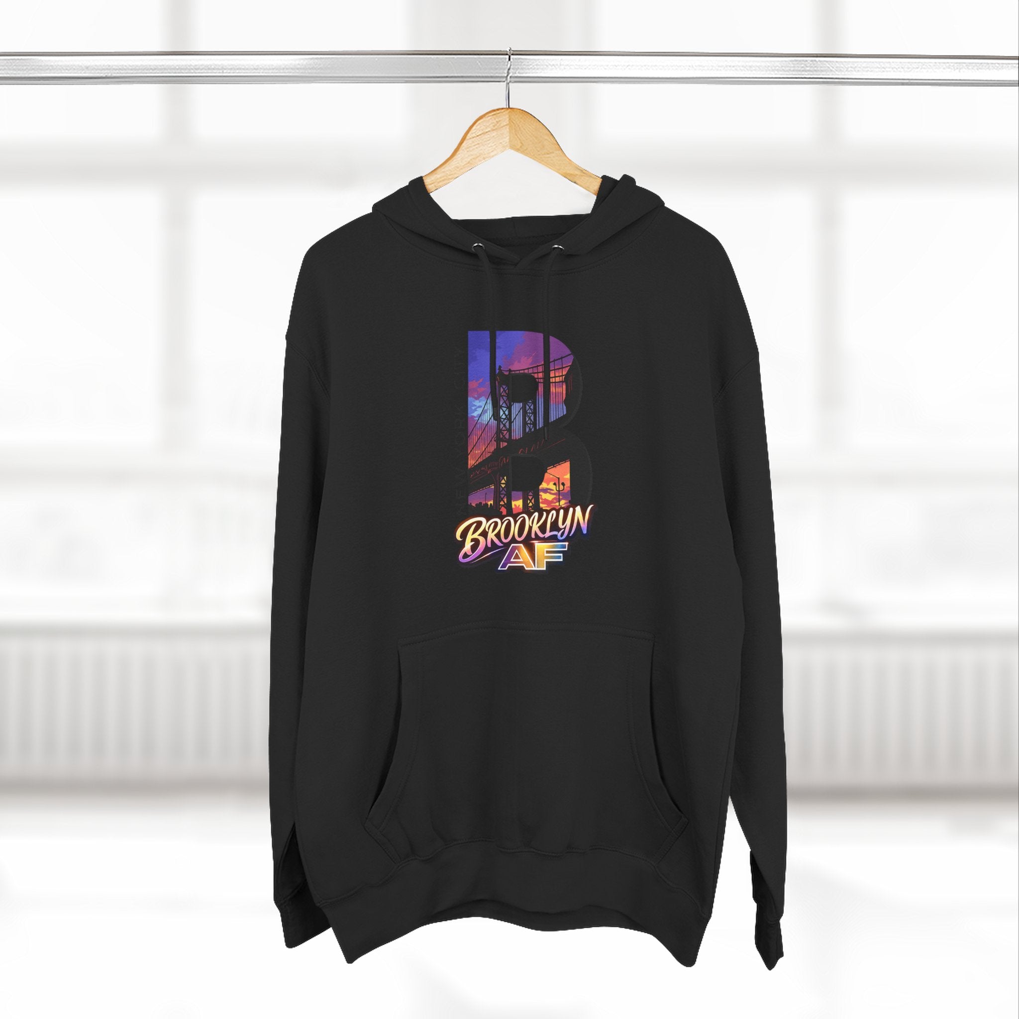 Black hoodie hanging on a wooden hanger, bold B with a Brooklyn Bridge sunset skyline graphic.