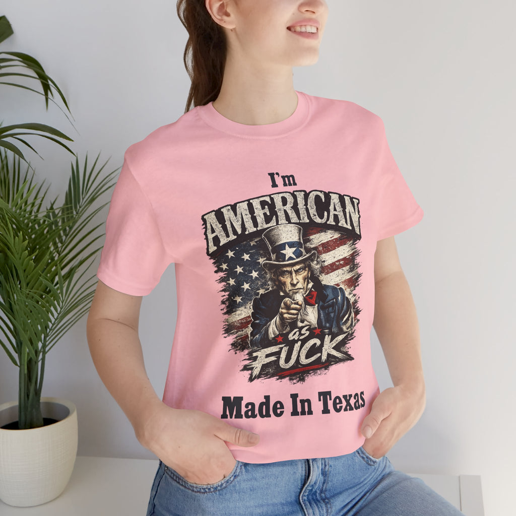 Pink tee worn by female model, close-up, Uncle Sam graphic with "I'm American As Fuck, Made In Texas" text
