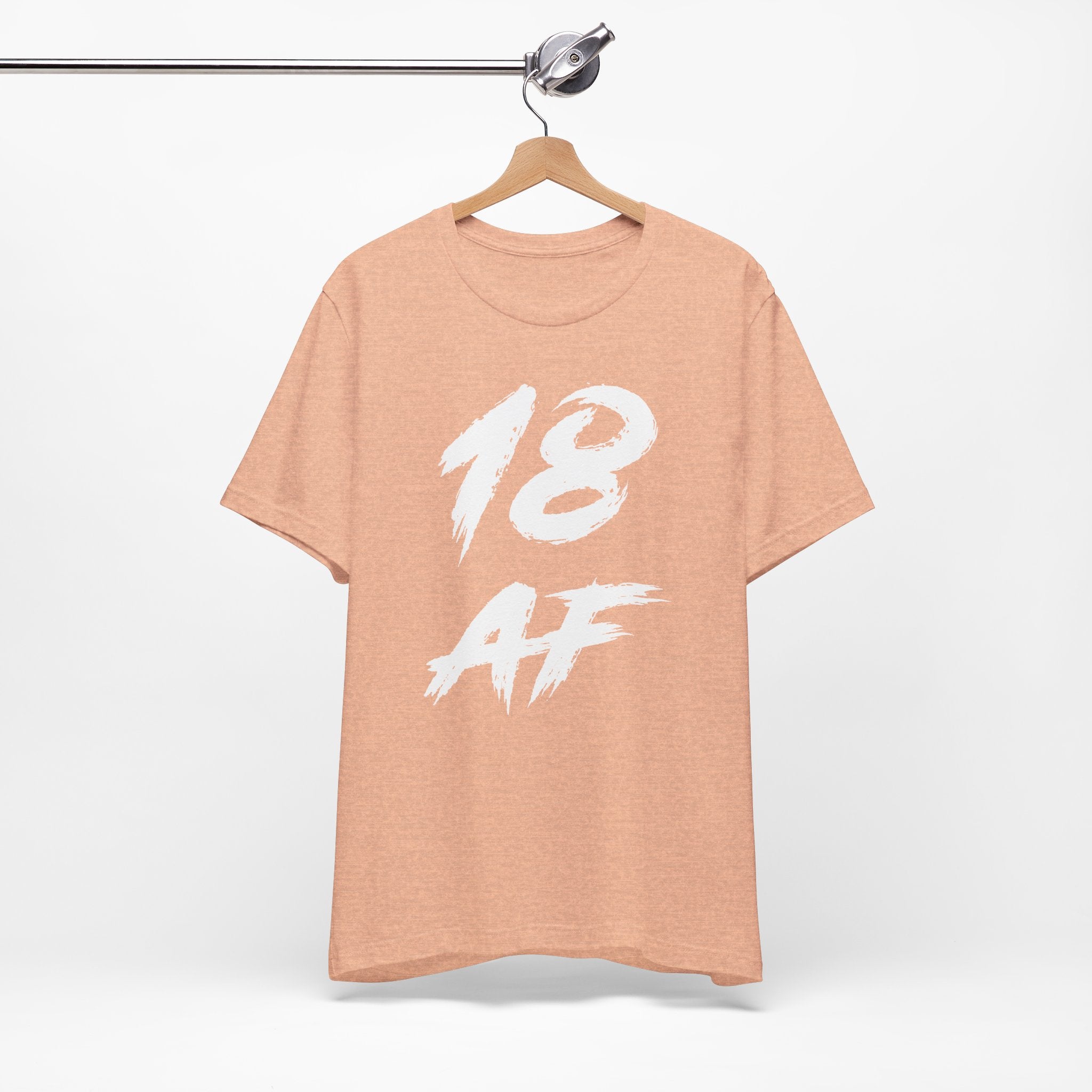 Heather Peach birthday tee on a wooden hanger showing the white front print