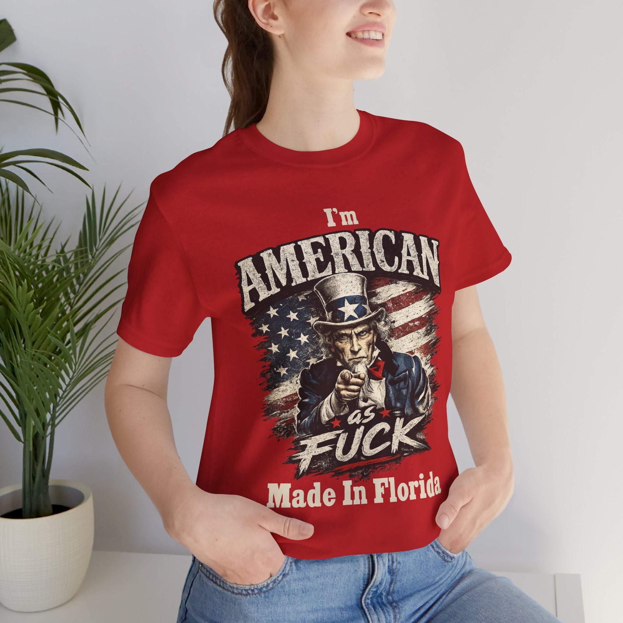 Close-up of a red t-shirt worn by a female model, showing Uncle Sam print detail near a plant