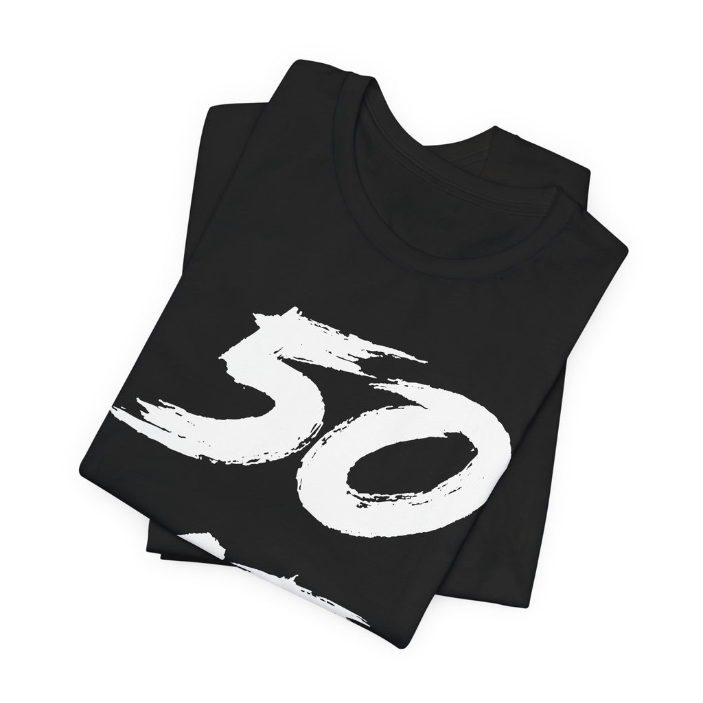 Folded black birthday tees stacked, the white 50 filling the top fold