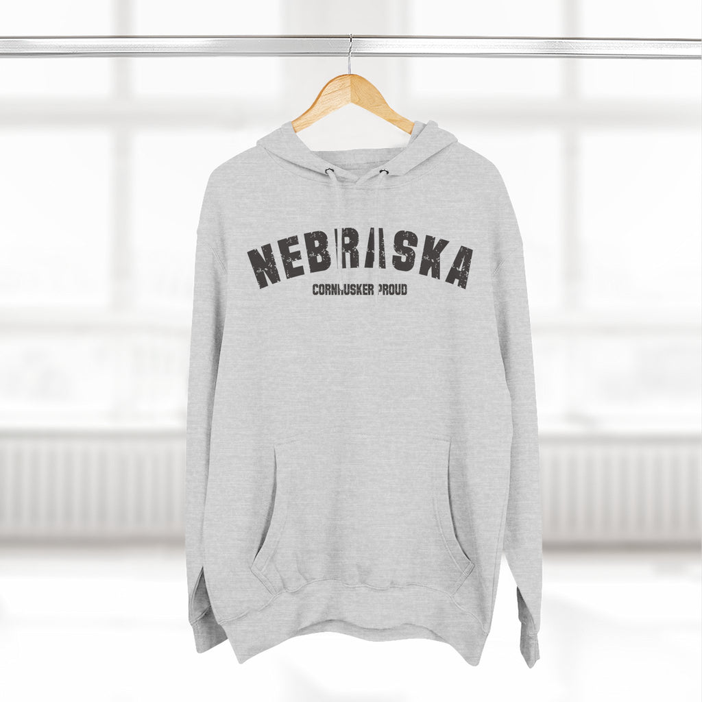 Heather Grey Nebraska hoodie hanging on a wooden hanger in front of a sunlit window
