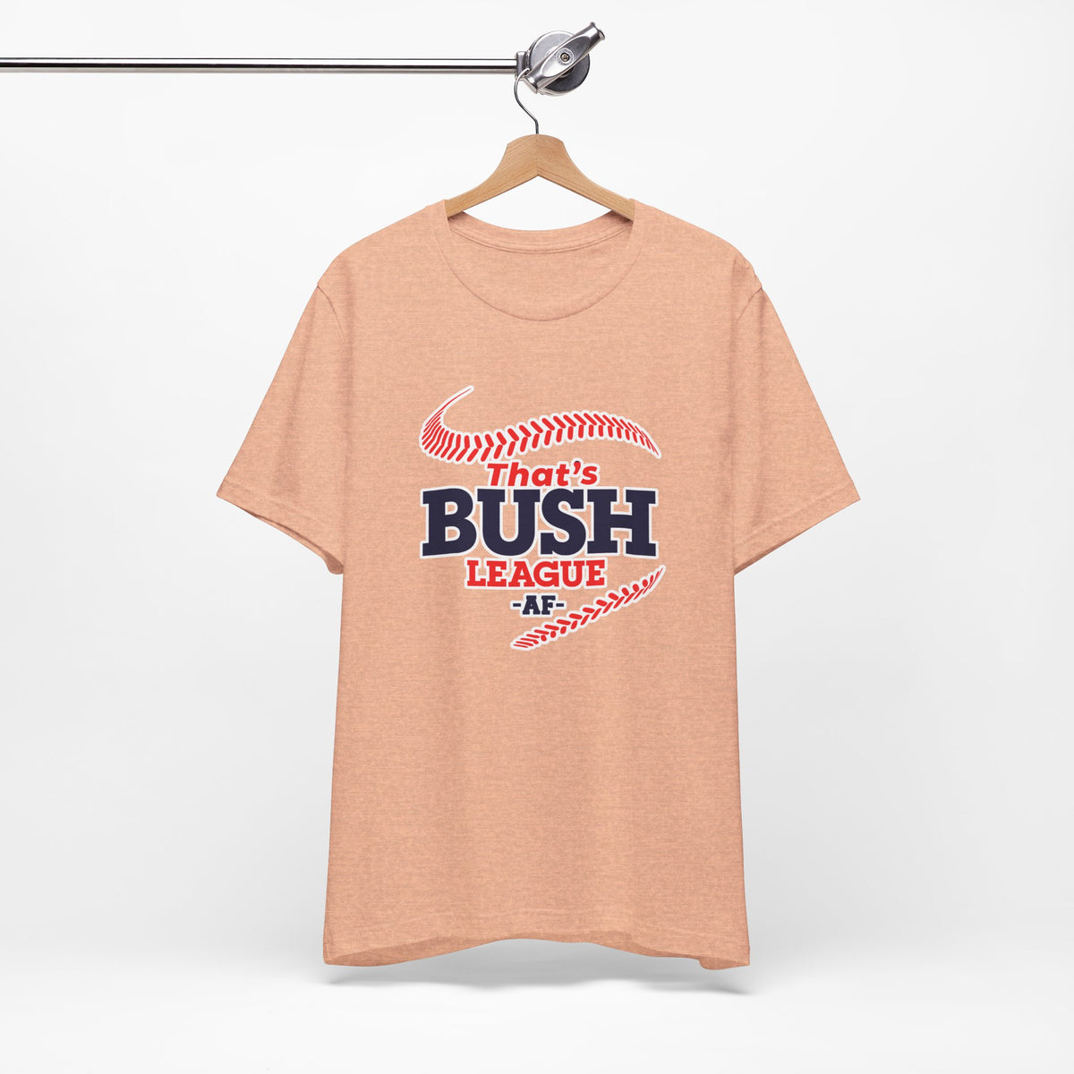 Heather Peach Bush League AF T-Shirt on a wooden hanger against a light wall