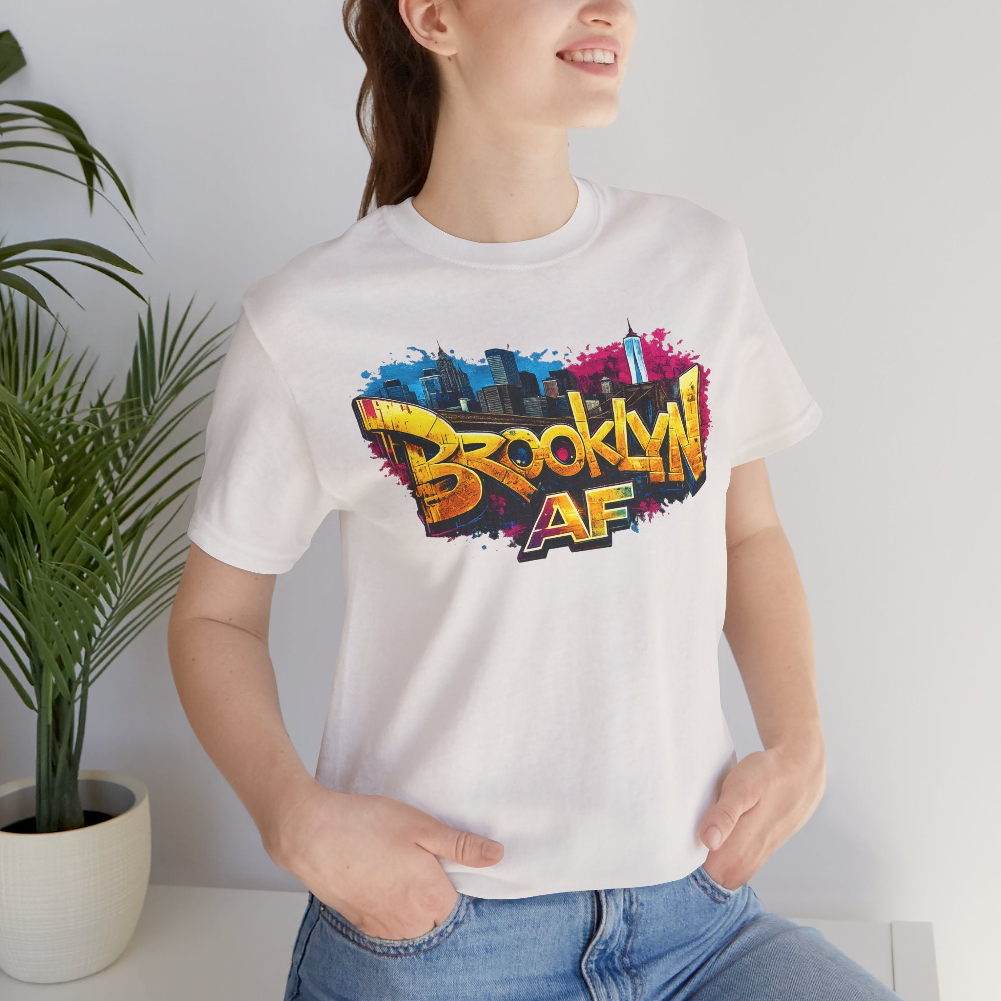 White t-shirt worn by a model, close-up of chest print showing graffiti Brooklyn AF lettering and skyline art.