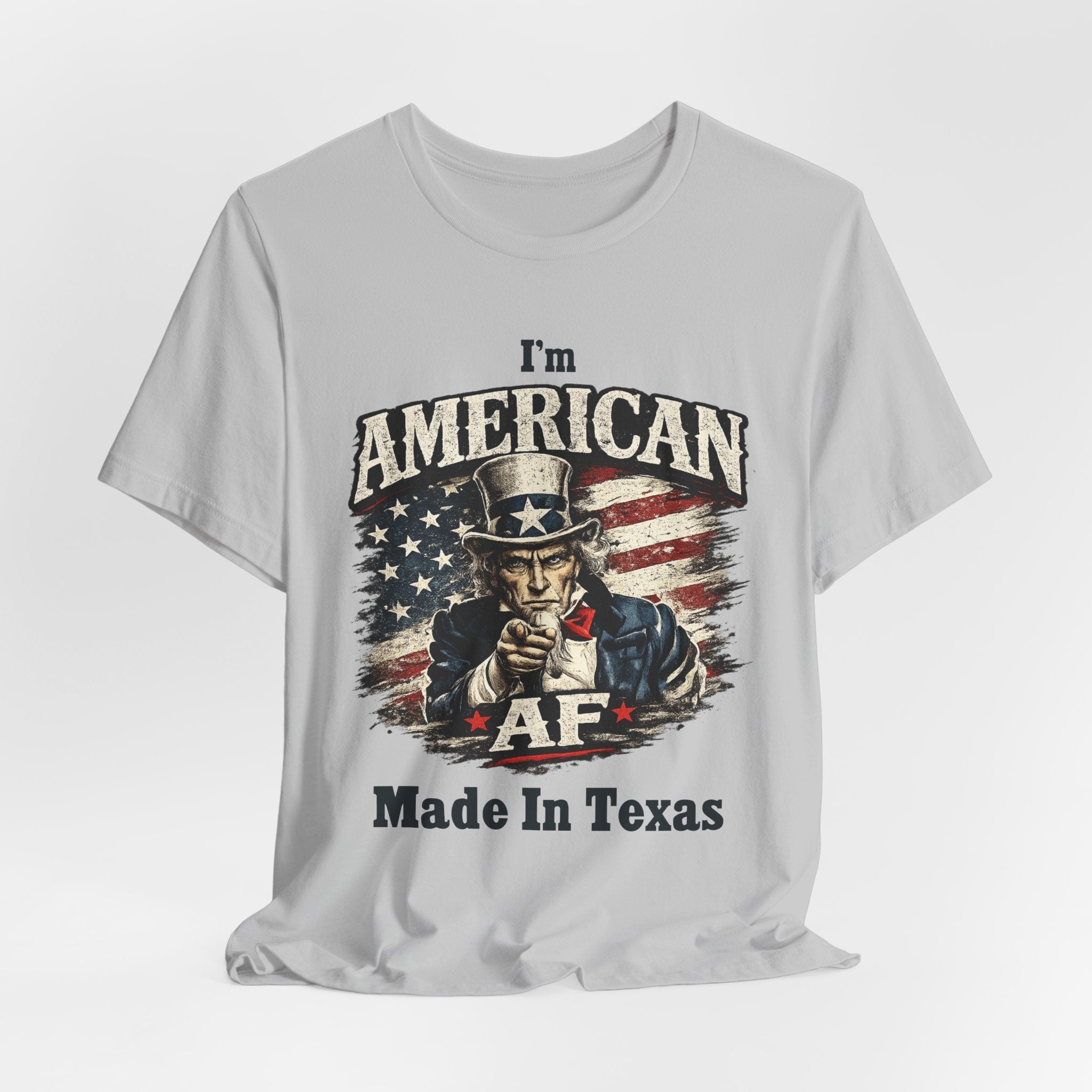 Light gray tee laid flat with relaxed drape, Uncle Sam graphic and 'I'm American AF, Made In Texas' text