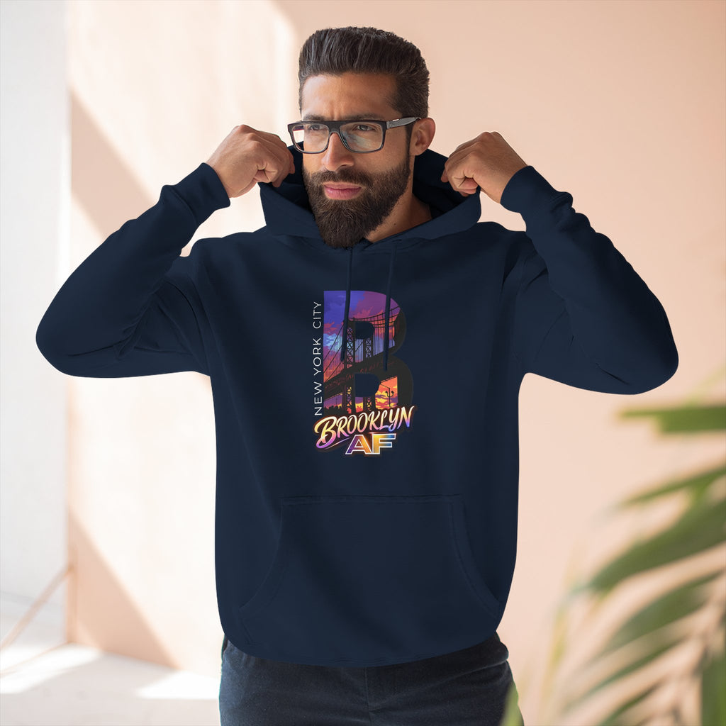 Navy hoodie worn by a male model, close-up front view adjusting the hood, showing the oversized "B" skyline graphic.