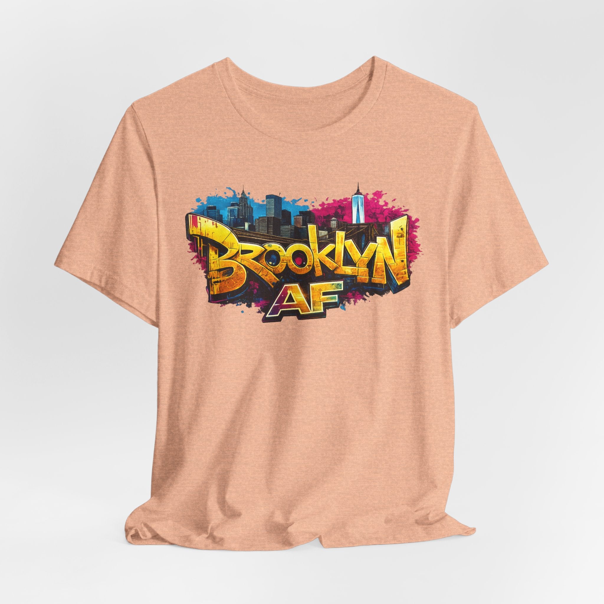 Heather Peach t-shirt, front view flat lay, showing graffiti Brooklyn AF lettering over a skyline paint splash.