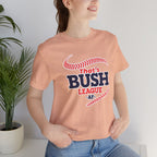 Woman wearing the Heather Peach Bush League AF tee beside a plant, navy lettering visible