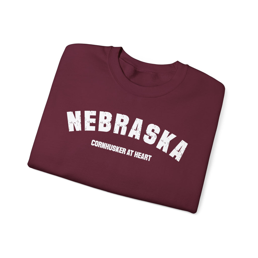 Maroon Nebraska sweatshirt folded at an angle, white distressed varsity print facing the camera