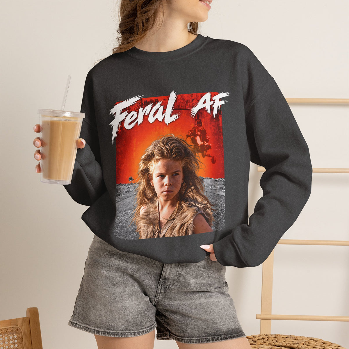 Woman wearing the Dark Heather Feral AF crewneck with an iced coffee, charcoal fabric