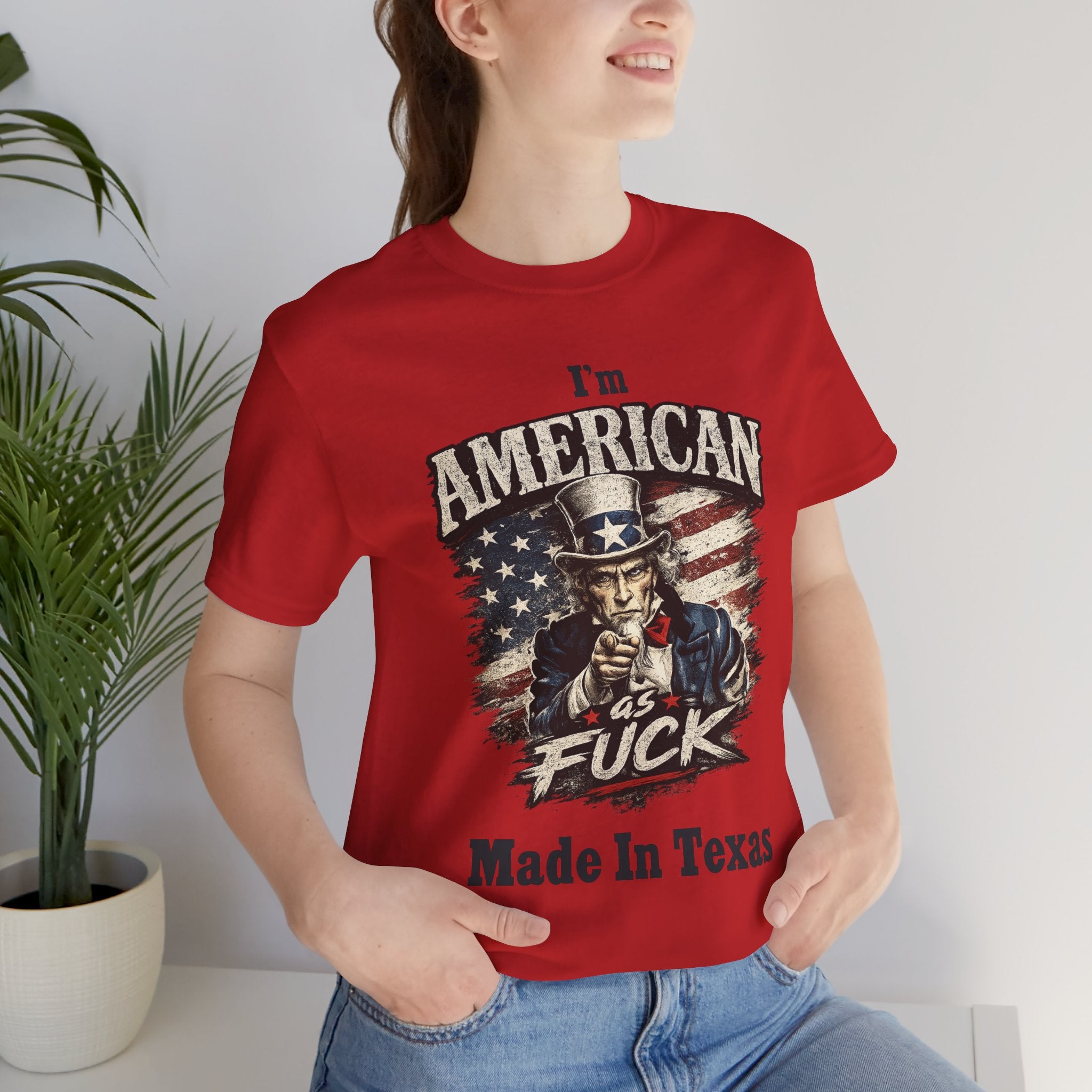 Red tee worn by female model, close-up, Uncle Sam graphic with "I'm American As Fuck, Made In Texas" text