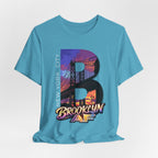 Teal t-shirt flat lay, front view with full 'B' graphic, Brooklyn Bridge sunset skyline and 'Brooklyn AF' logo