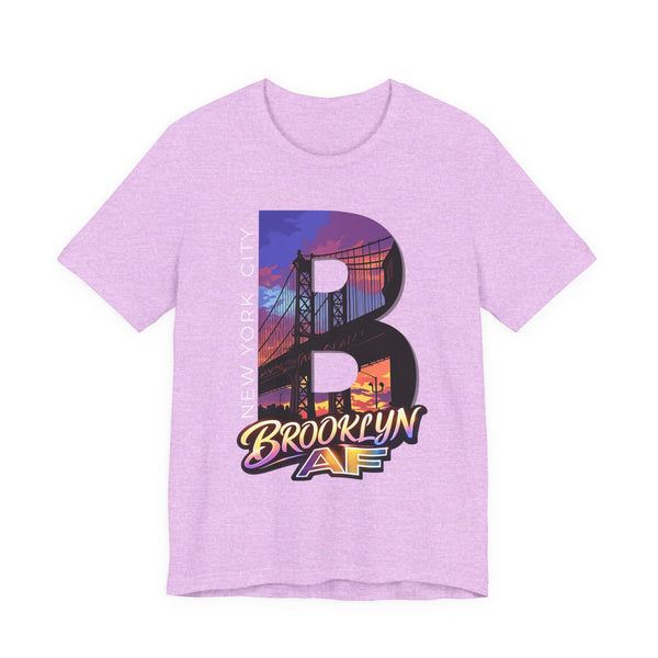 Heather prism lilac t-shirt, flat lay front view, with a bold B and a purple-orange Brooklyn Bridge sunset skyline graphic.