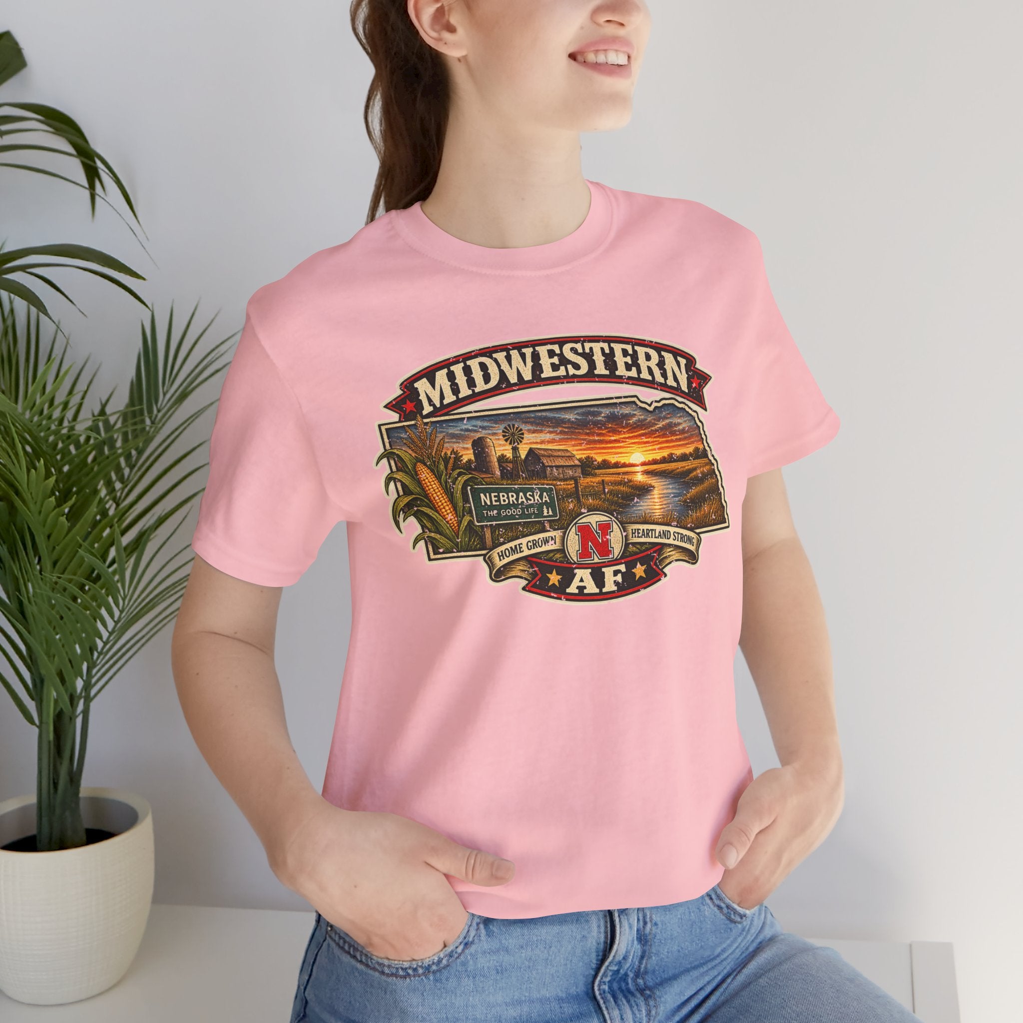 Close crop of the pink Nebraska T-shirt on a model, Midwestern lettering above the farm scene