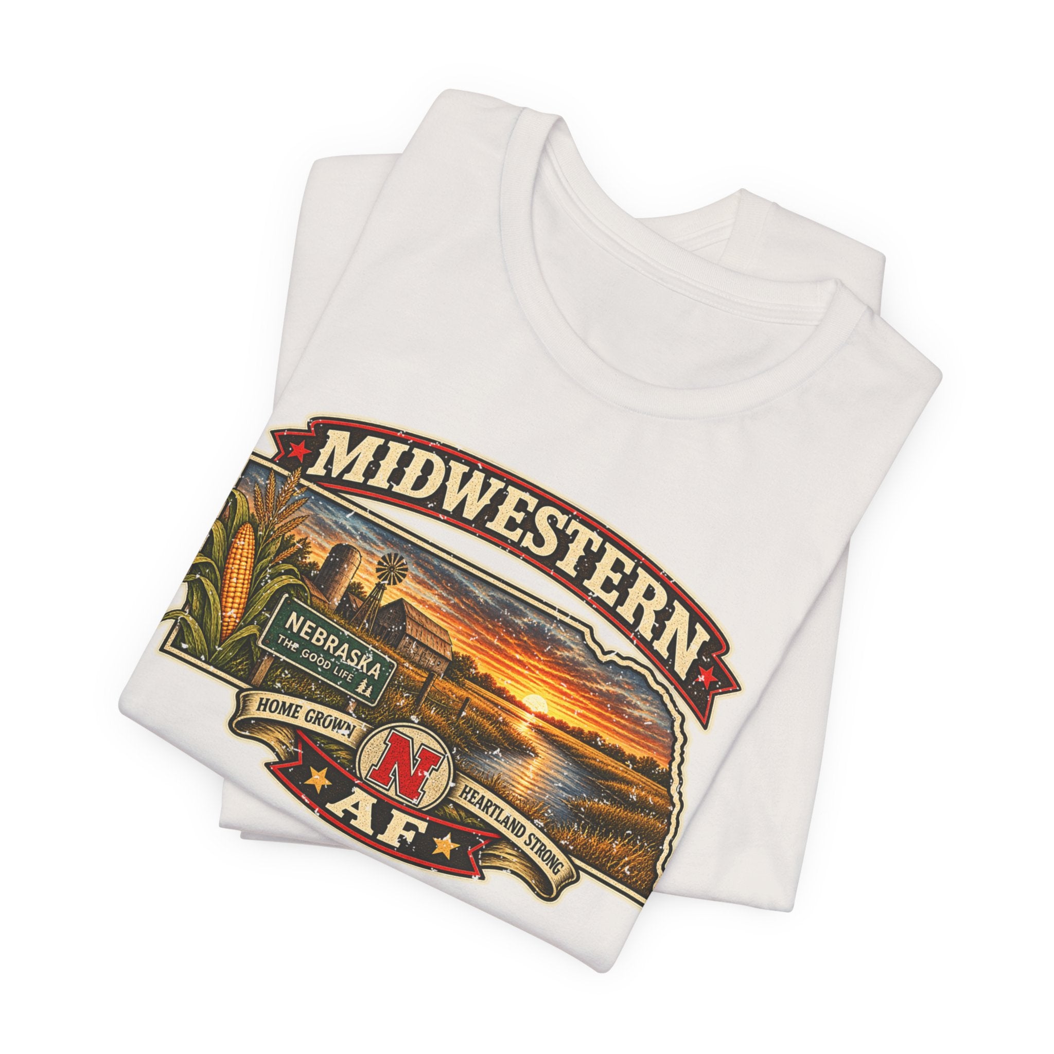 Folded natural Nebraska tee, close on the Nebraska The Good Life sign and red N crest