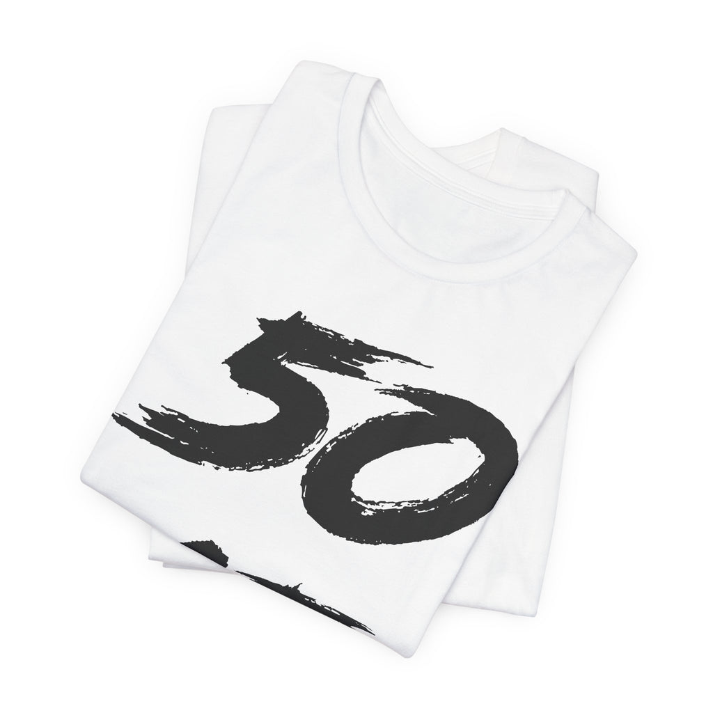Folded white birthday tees stacked, the black 50 showing on the top fold