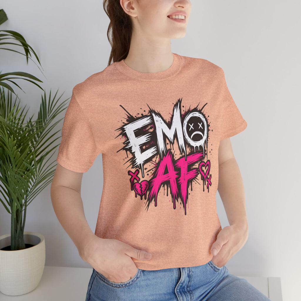 Woman wearing the Heather Peach EMO AF tee beside a plant