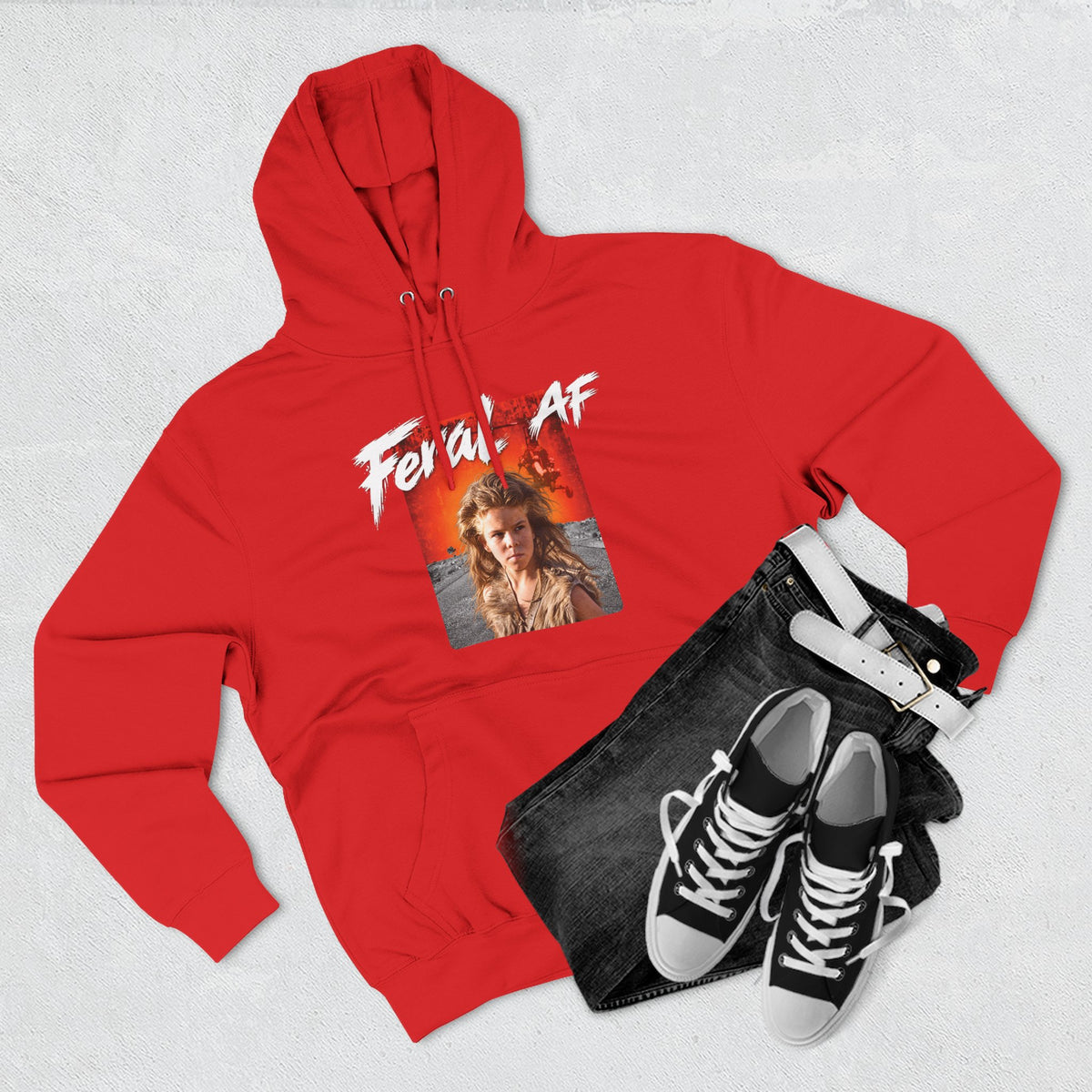 Red Feral AF hoodie styled flat with folded jeans and canvas sneakers, front print showing