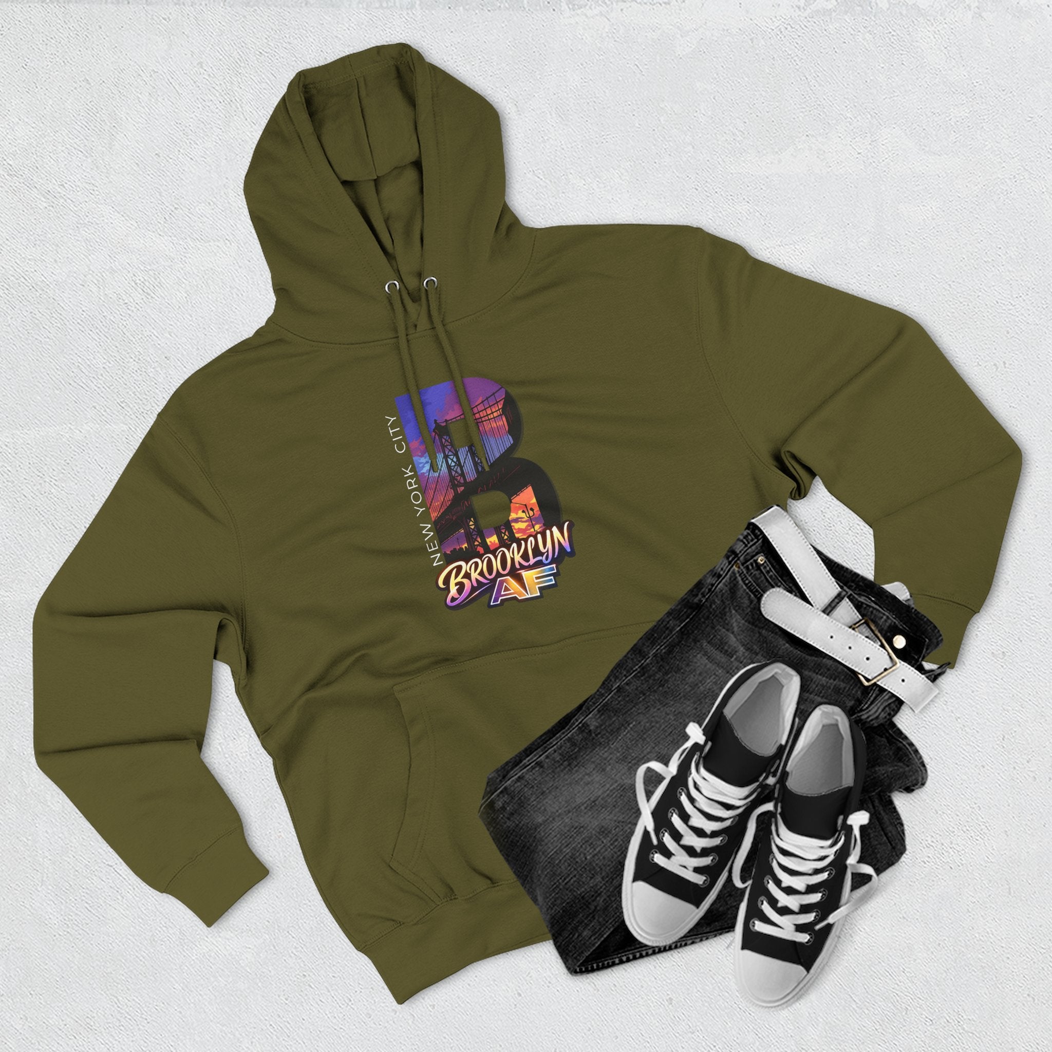 Army green hoodie flat lay styled with jeans, white belt, and sneakers, showing the oversized "B" skyline graphic.
