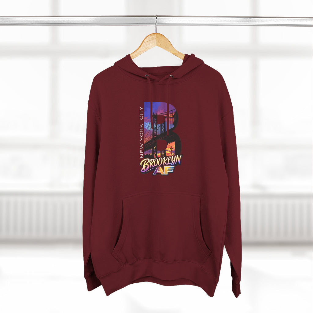 Maroon hoodie on a hanger, front view, featuring the oversized B Brooklyn Bridge skyline graphic.