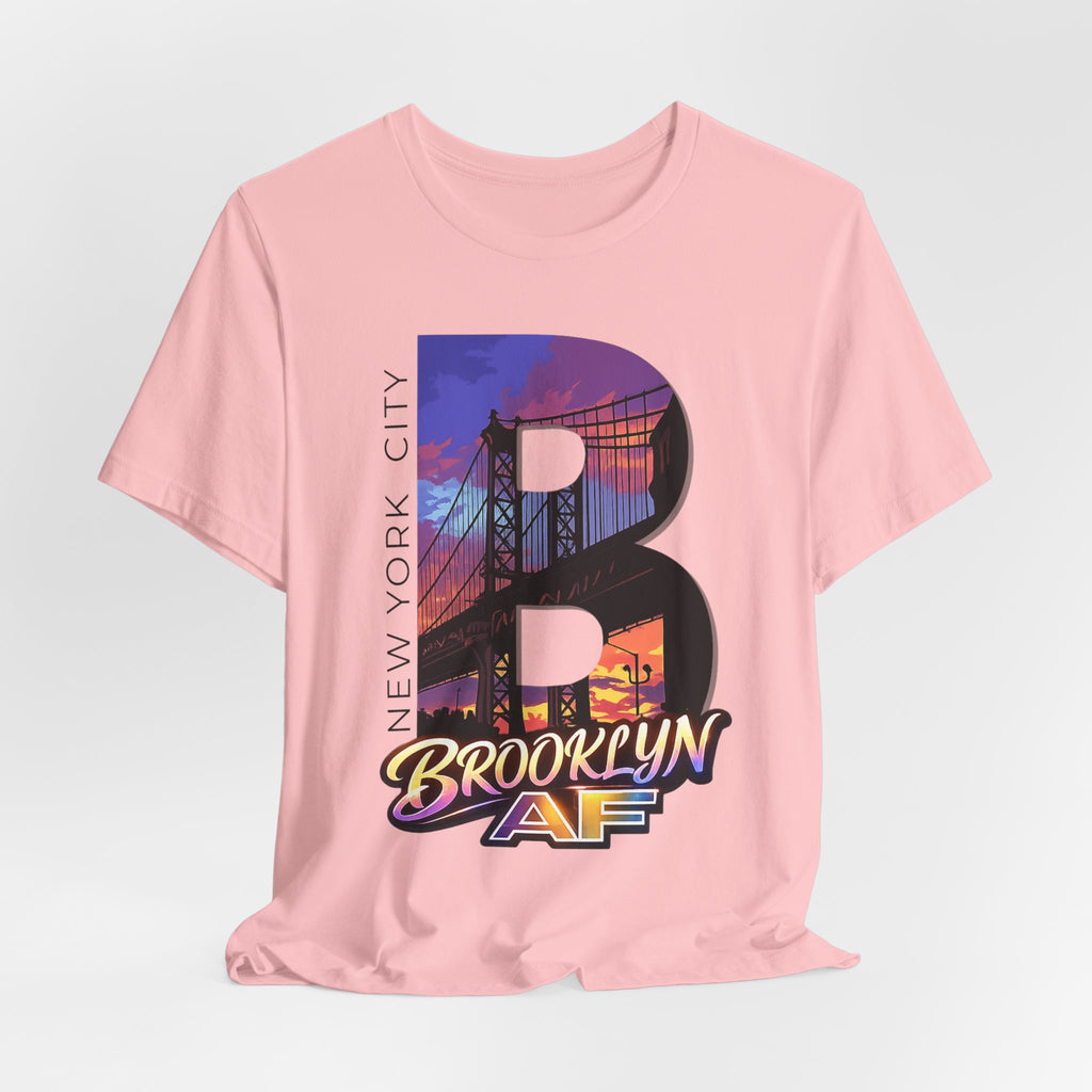 Pink tee, flat lay, front view, with the oversized "B" Brooklyn Bridge sunset skyline graphic and "Brooklyn AF" logo.
