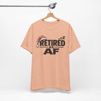 Heather Peach Retired AF T-shirt hanging on a wooden hanger against a plain wall