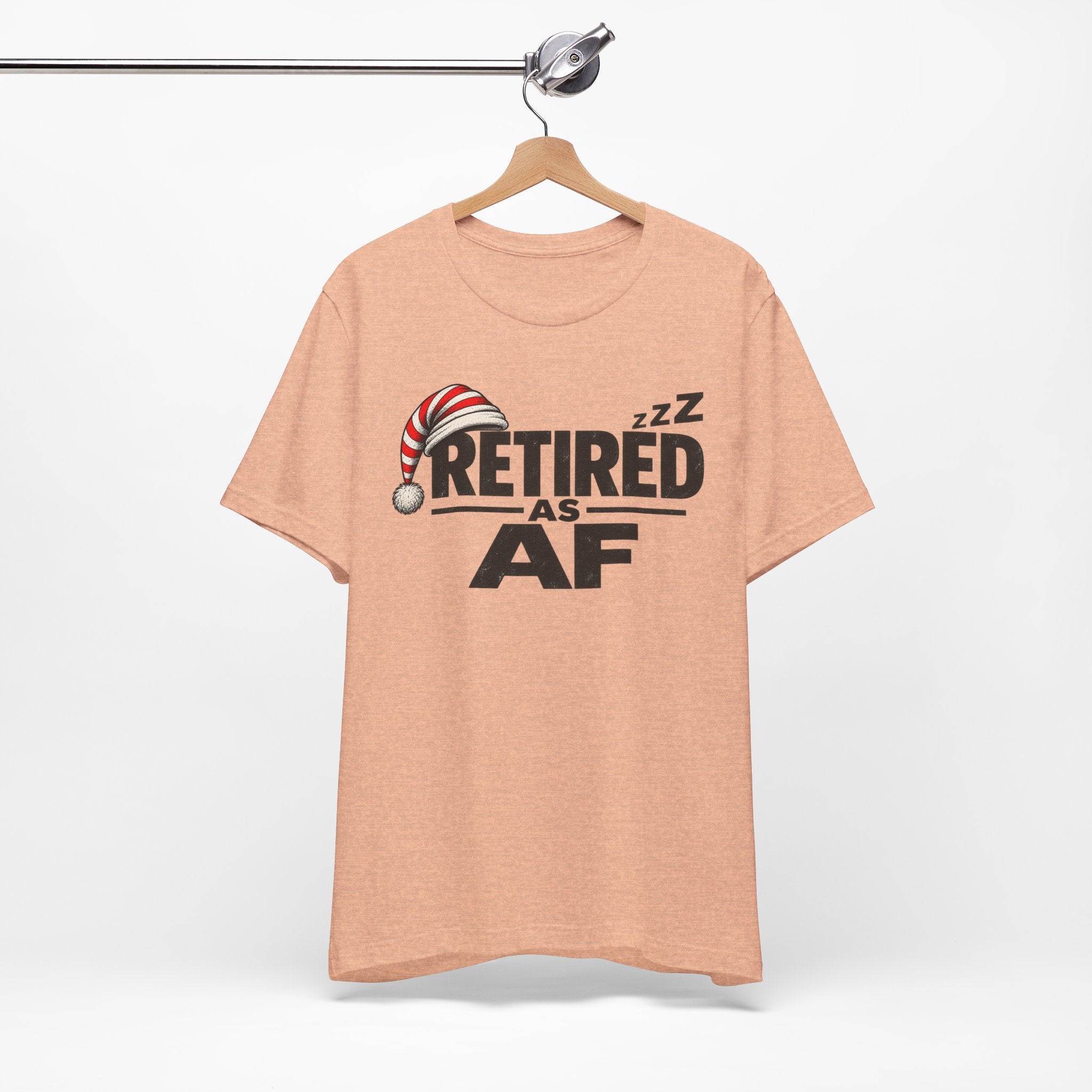 Heather Peach Retired AF T-shirt hanging on a wooden hanger against a plain wall