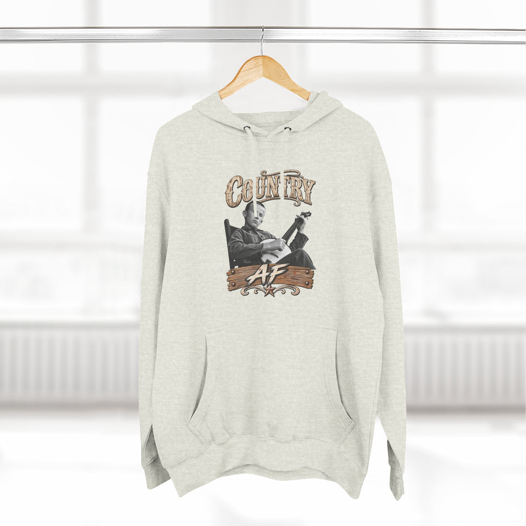 Oatmeal Heather Country AF hoodie on a wooden hanger by a window