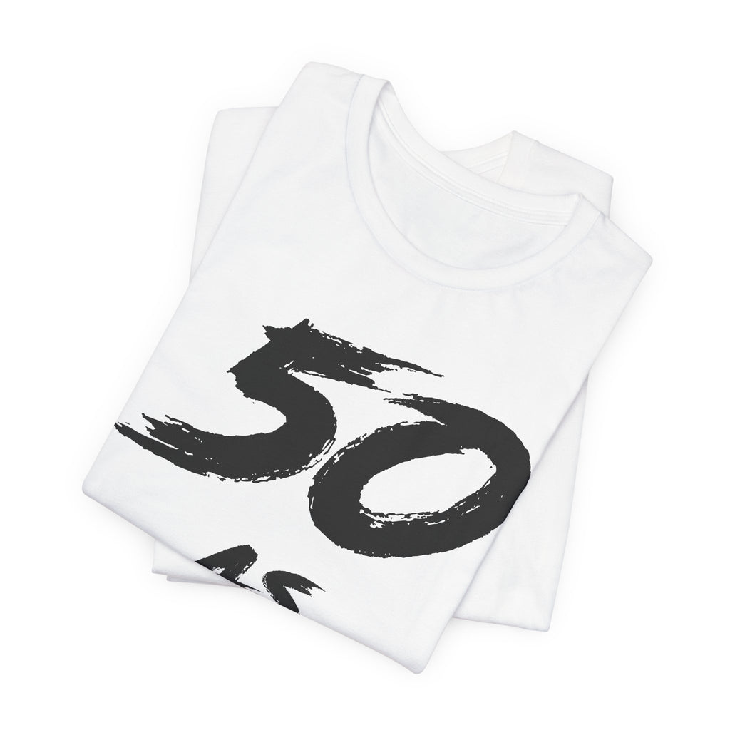 Folded white birthday tees stacked, the black 50 showing on the top fold