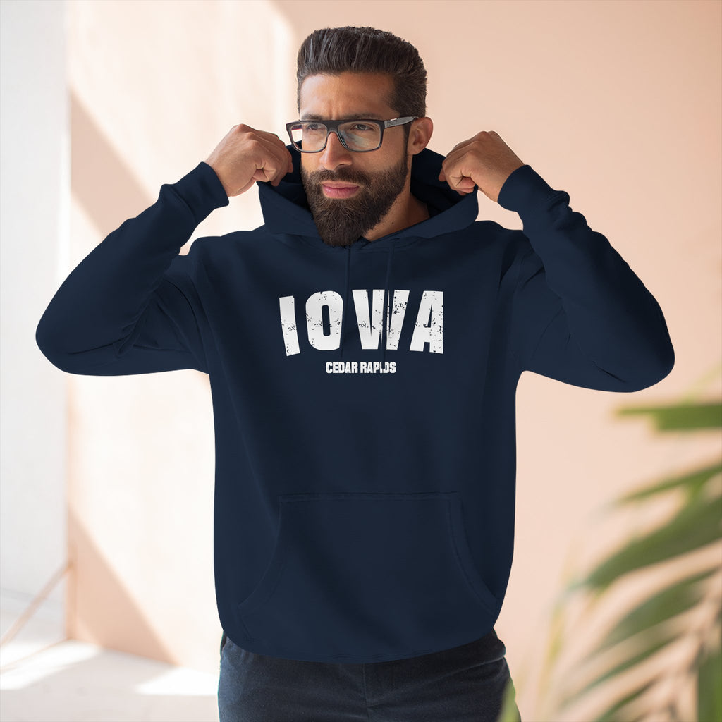 Bearded man pulling up the hood of the navy personalized Iowa hoodie printed IOWA CEDAR RAPIDS