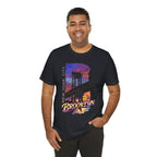 Black t-shirt worn by a smiling model, front view showing the 'B' Brooklyn Bridge sunset skyline graphic and logo