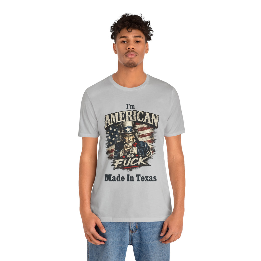 Light gray tee worn by curly-haired male model, Uncle Sam graphic with "I'm American As Fuck, Made In Texas" text