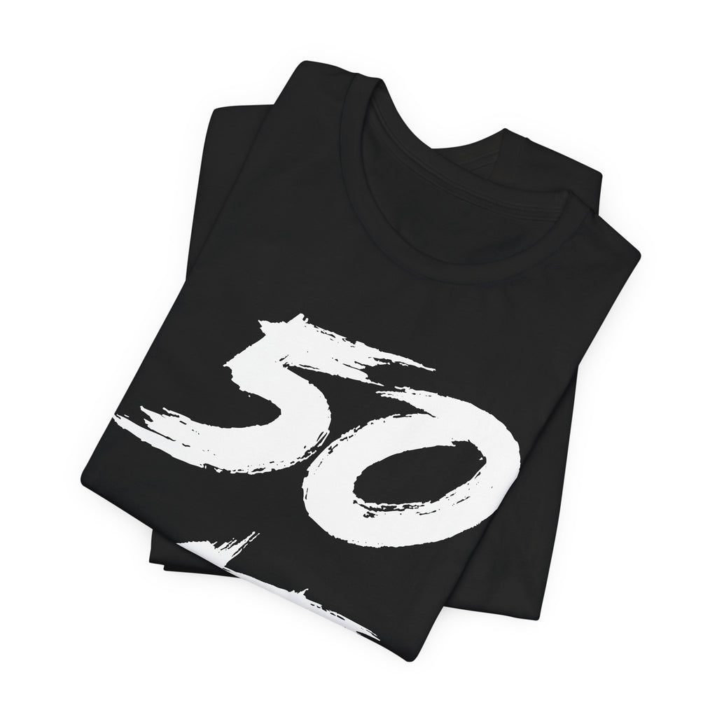 Folded black birthday tees stacked, the white 50 print filling the top fold