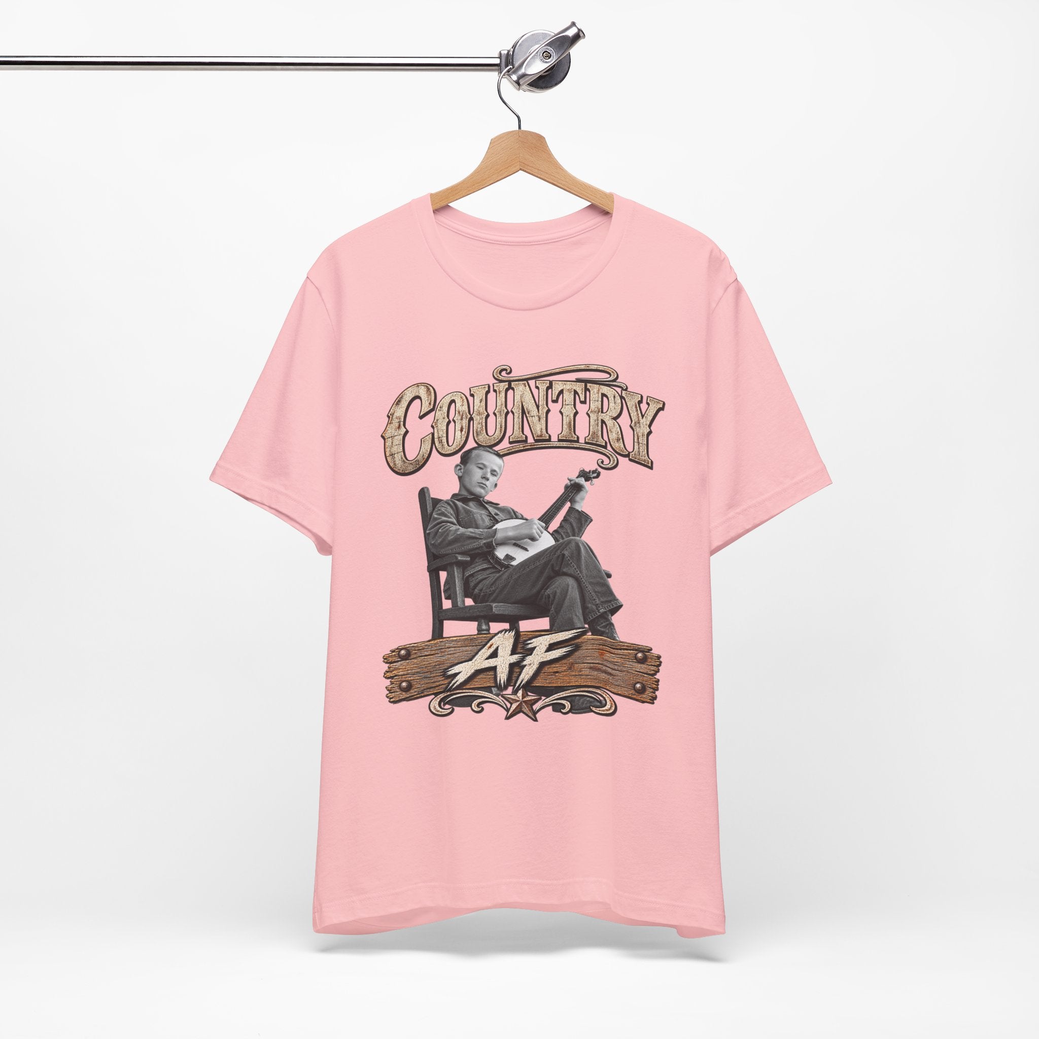 Pink Country AF tee on a wooden hanger, banjo front print showing