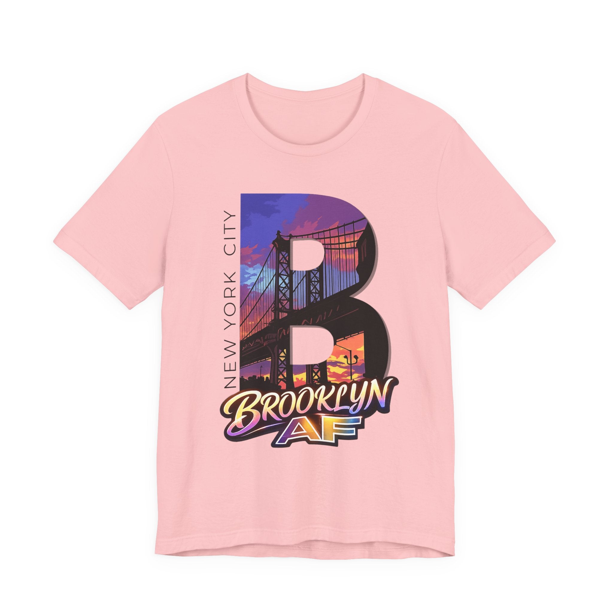 Pink t-shirt, flat lay, with a bold oversized "B" featuring a Brooklyn Bridge sunset skyline graphic.
