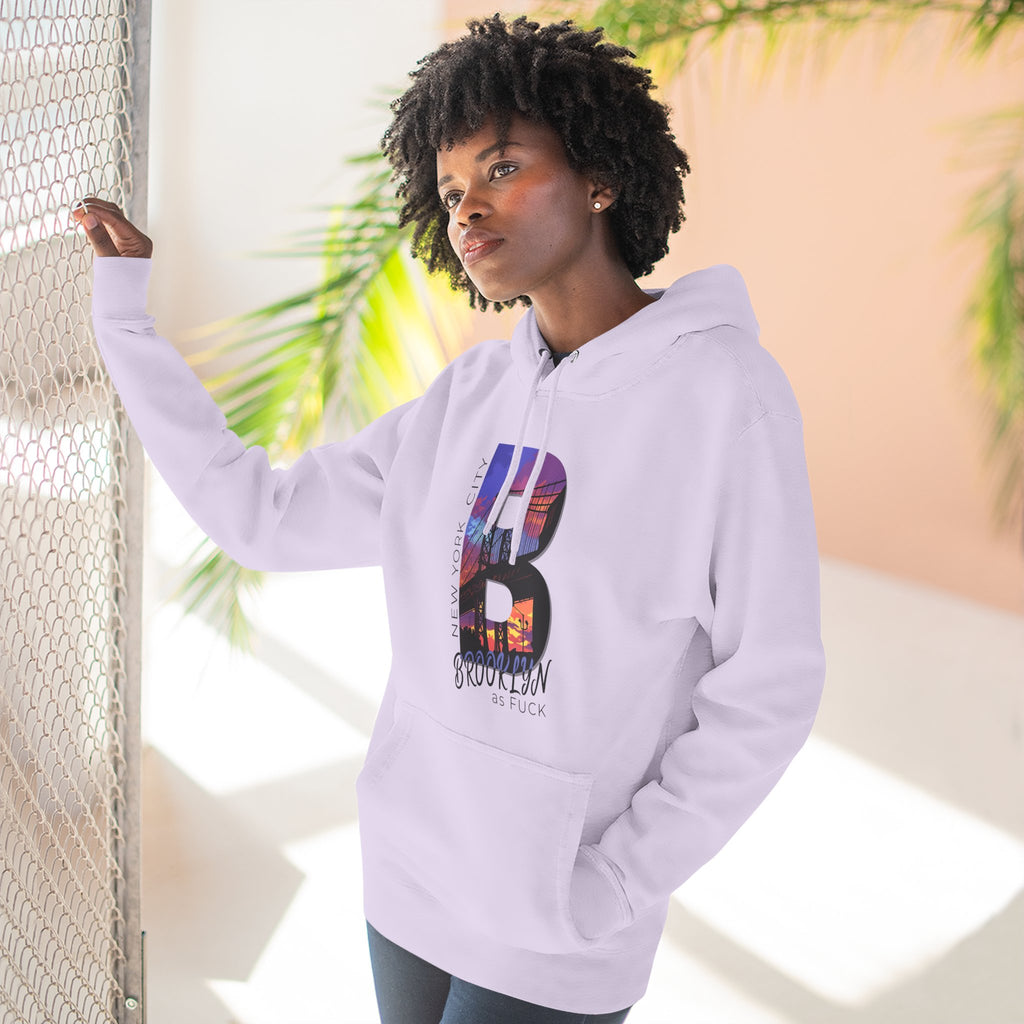 Lilac hoodie worn by a model outdoors near a fence, showing the bold 'B' Brooklyn skyline graphic and 'As Fuck' text.