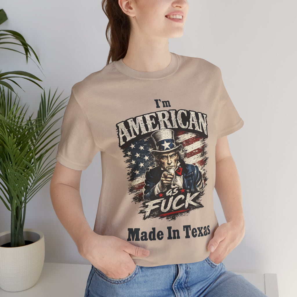 Sand tee worn by female model, close-up, Uncle Sam graphic with "I'm American As Fuck, Made In Texas" text