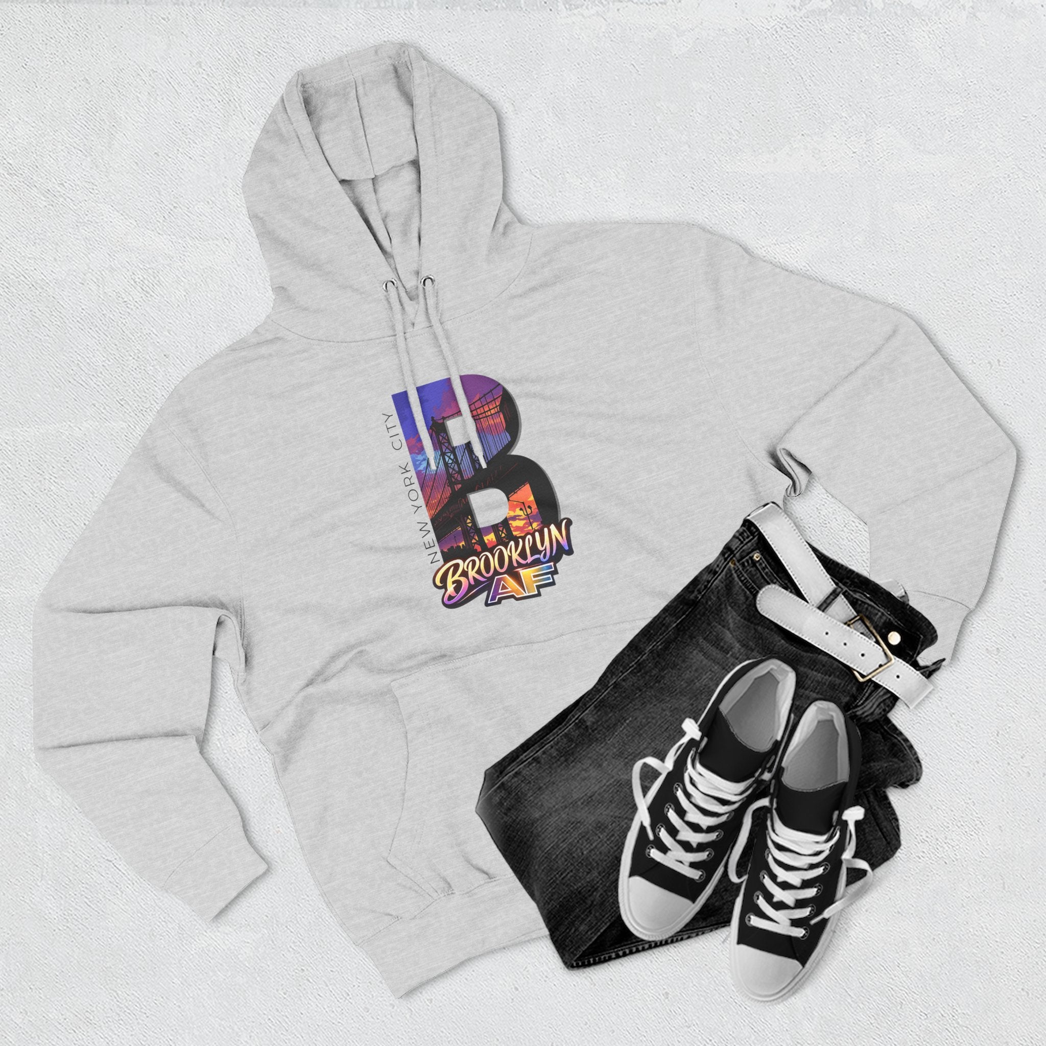 Heather grey hoodie styled with black jeans, belt, and sneakers, bold B with a Brooklyn Bridge sunset skyline graphic.
