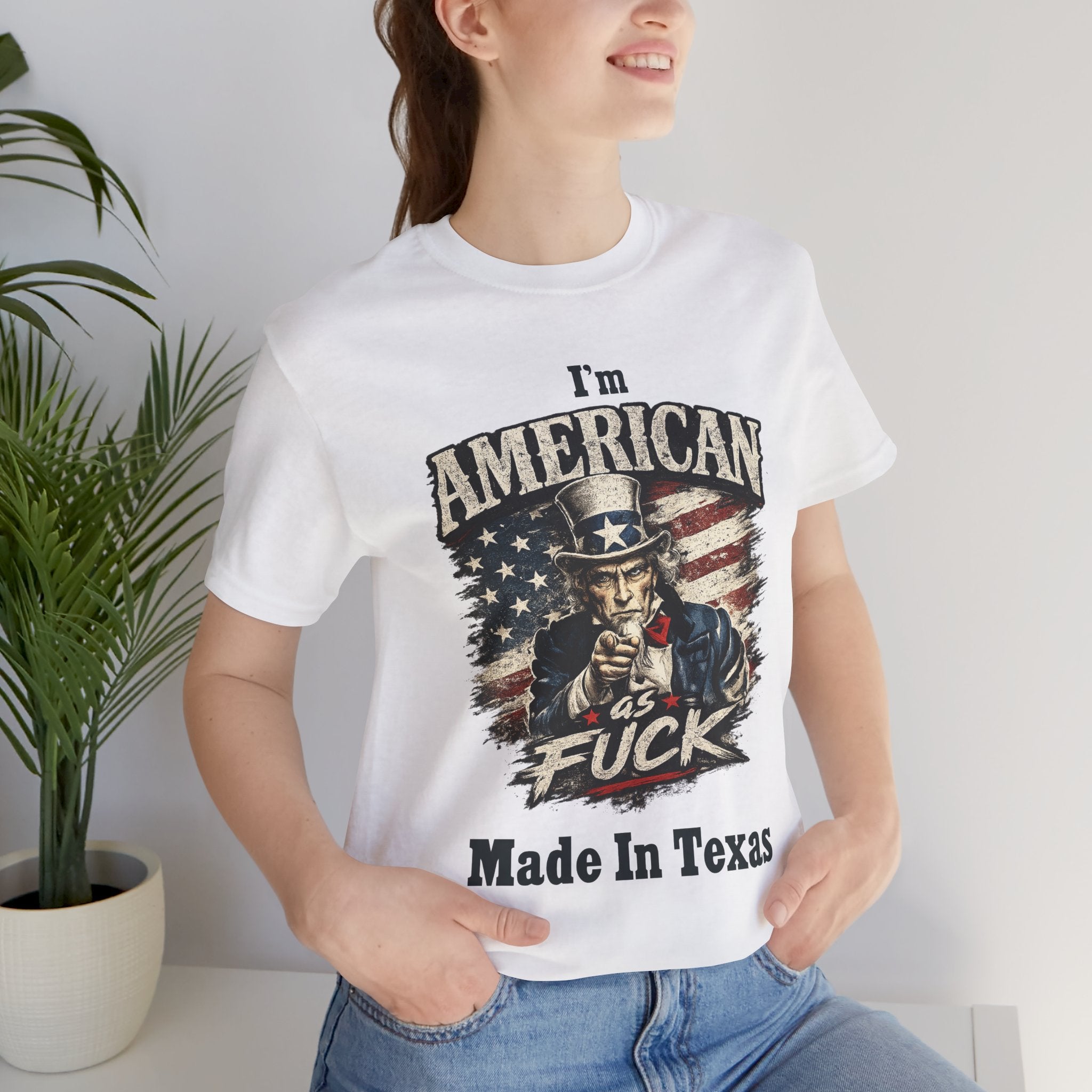 White tee worn by female model, close-up, Uncle Sam graphic with "I'm American As Fuck, Made In Texas" text
