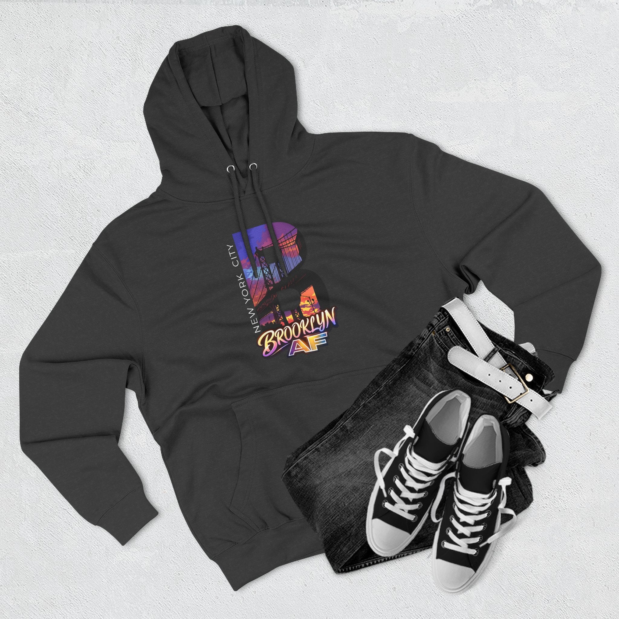 Black hoodie flat lay styled with jeans, white belt, and sneakers, showing the oversized "B" skyline graphic.