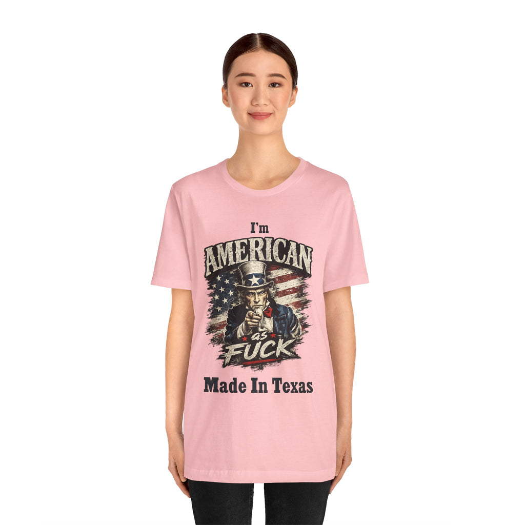 Pink tee worn by female model, close-up, Uncle Sam graphic with "I'm American As Fuck, Made In Texas" text