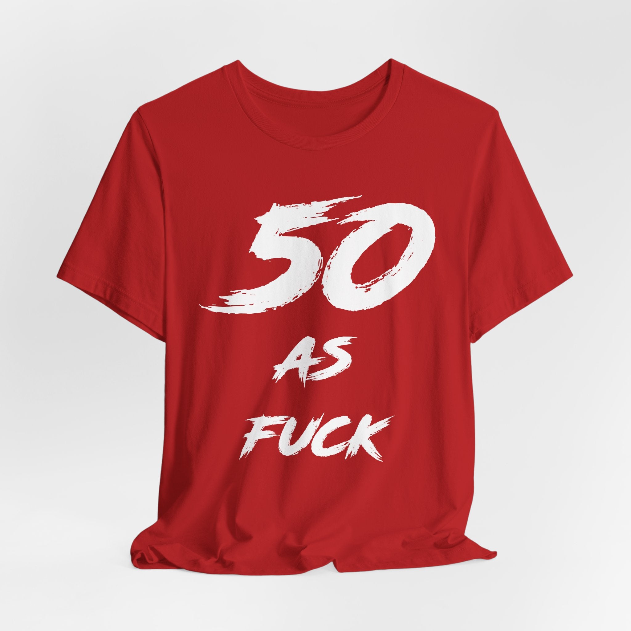 Red birthday t-shirt laid flat and slightly rumpled, white 50 AS FUCK front graphic