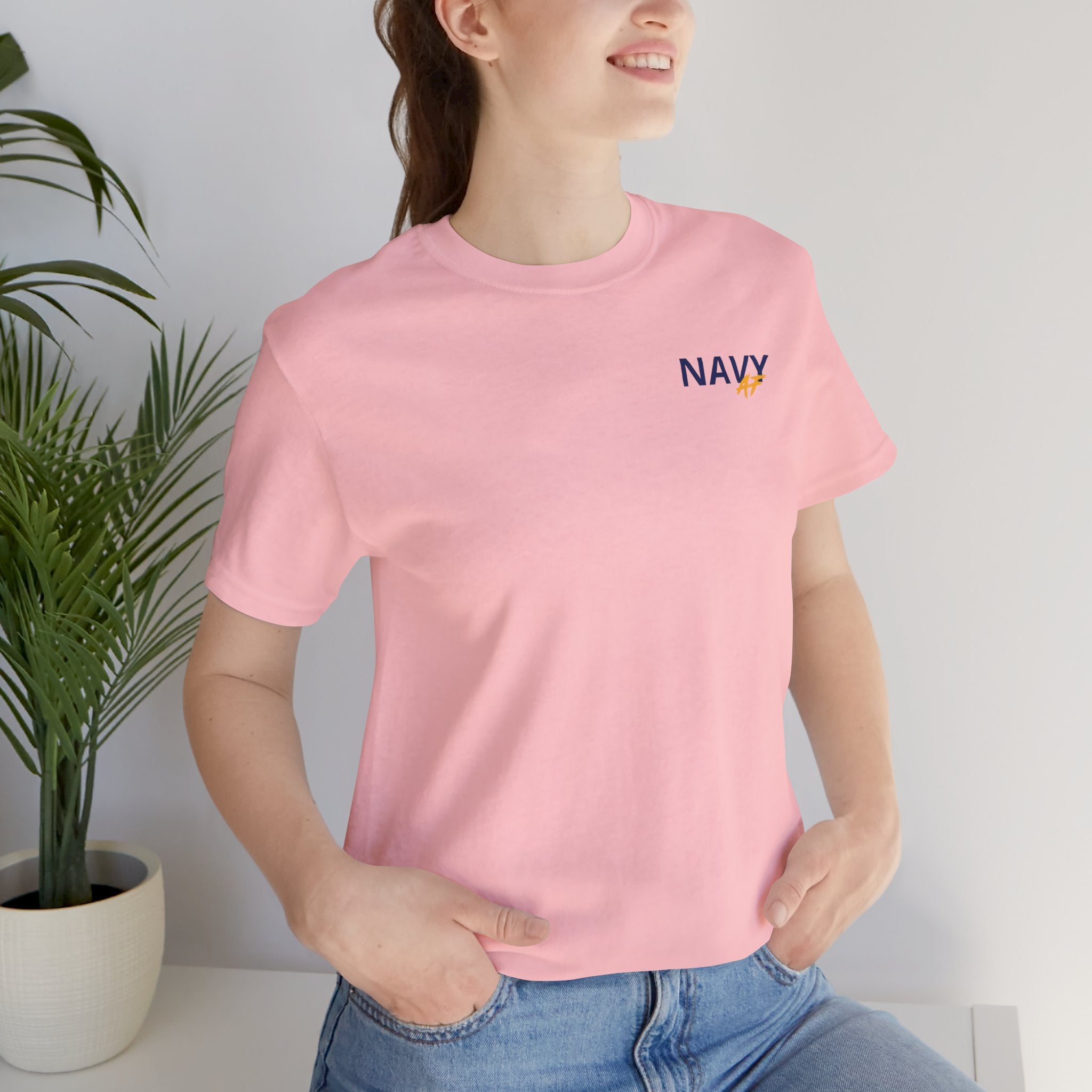 Woman wearing the Navy veteran T-shirt in Pink beside a potted plant