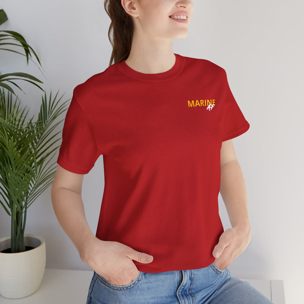 Woman wearing the Marine Corps veteran T-shirt in Red beside a potted plant